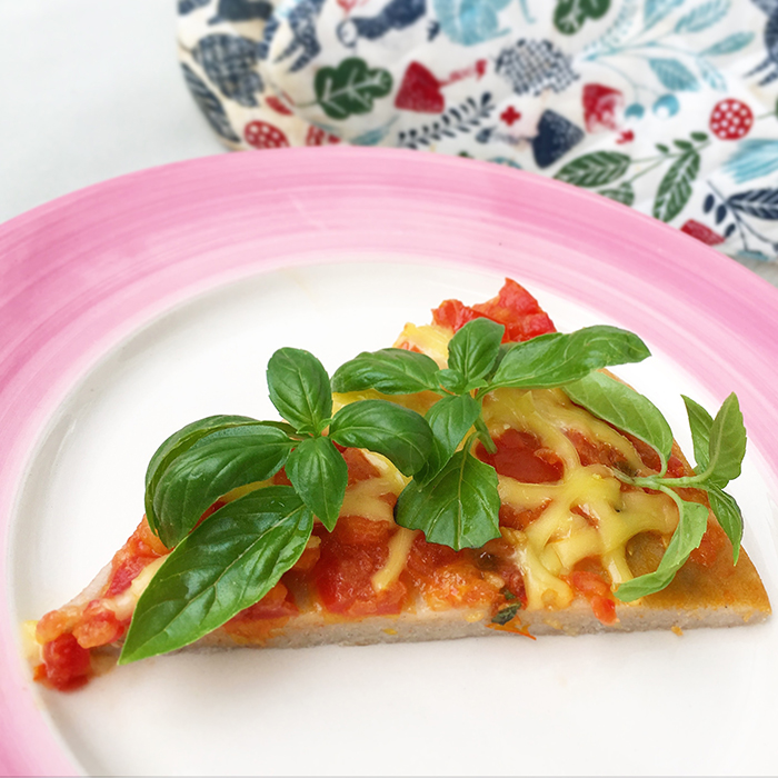 En vegansk och glutenfri pizza slice ligger på ett fat.