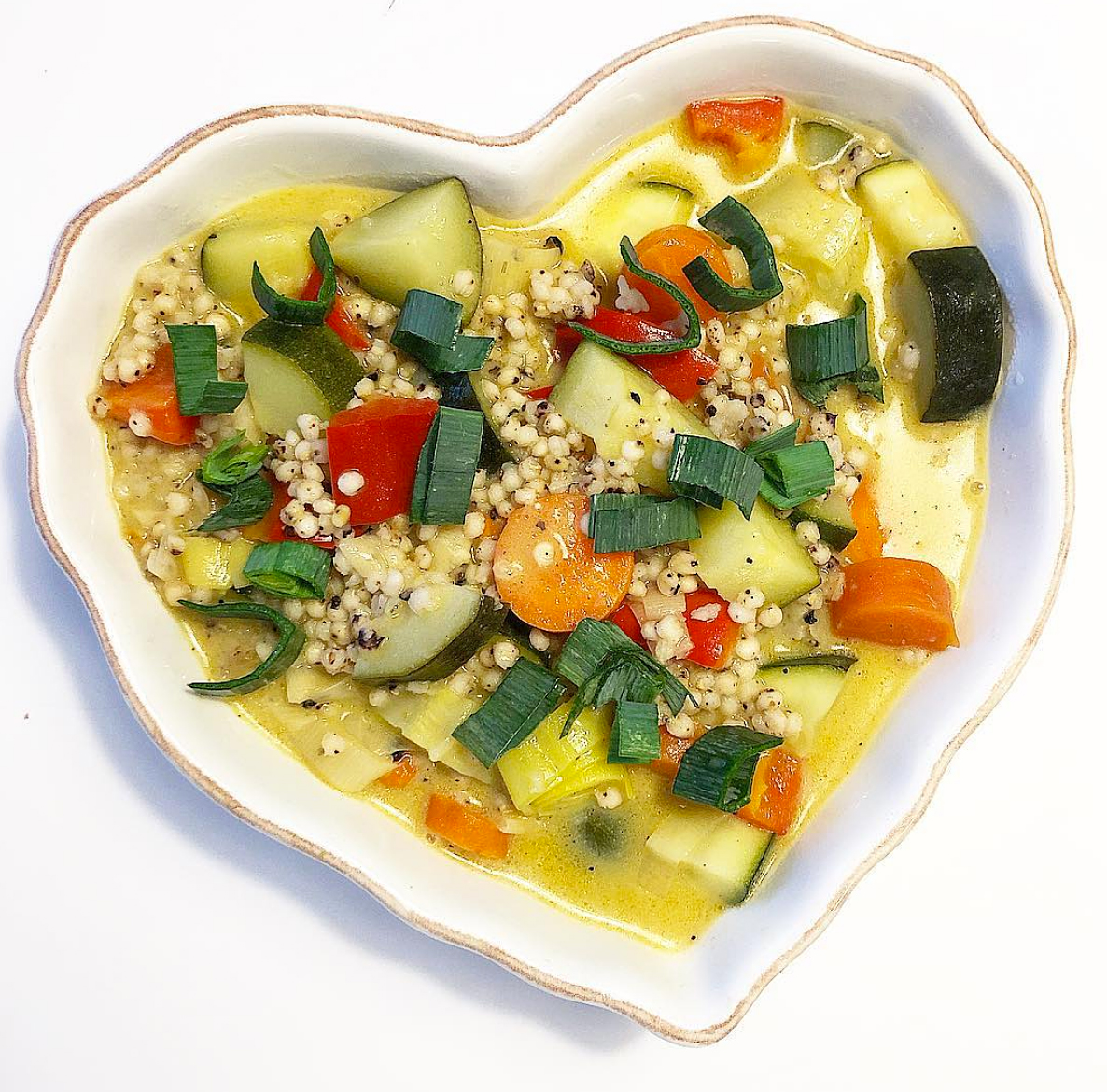 Foto på vegansk grönsaksragu med durrakorn serverat i ett hjärtformat vitt fat