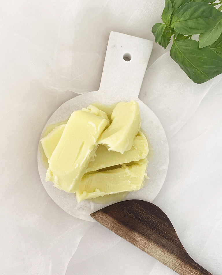Ett fat med hemmagjort veganskt margarin med en basilikakvist vid sidan om. 