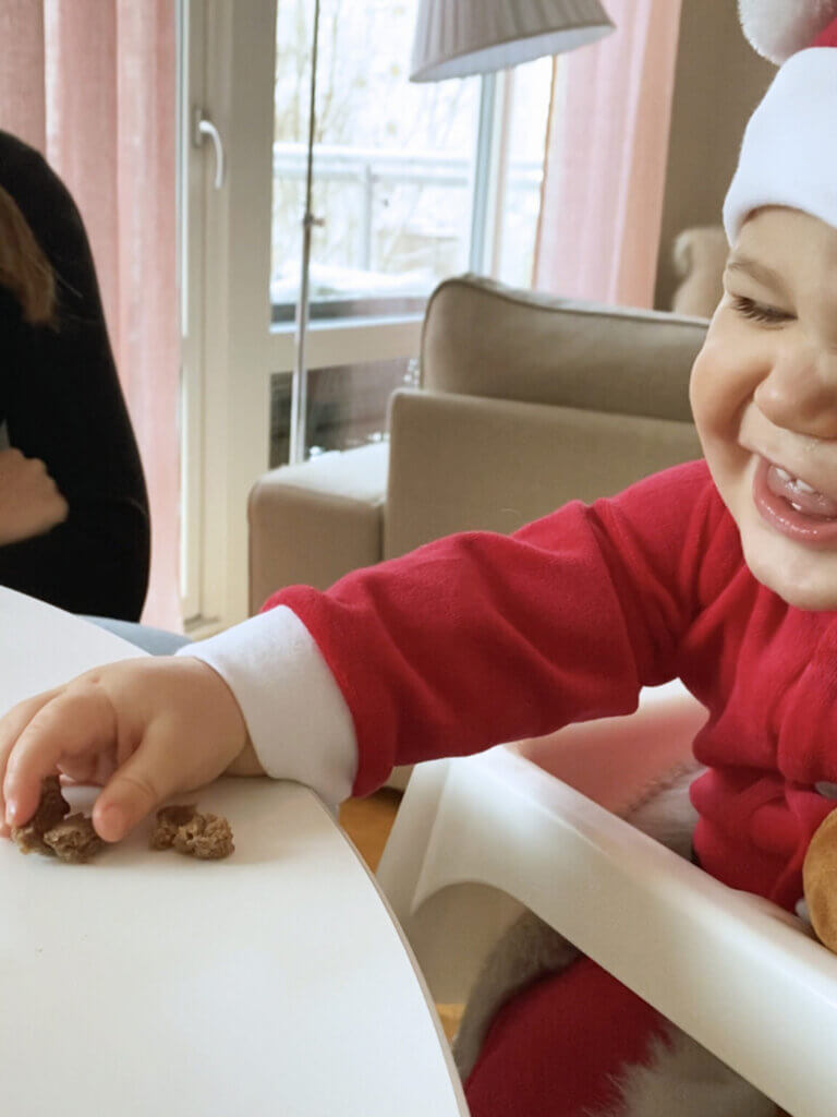 En bebis sitter vid ett bord och äter bananmuffins.