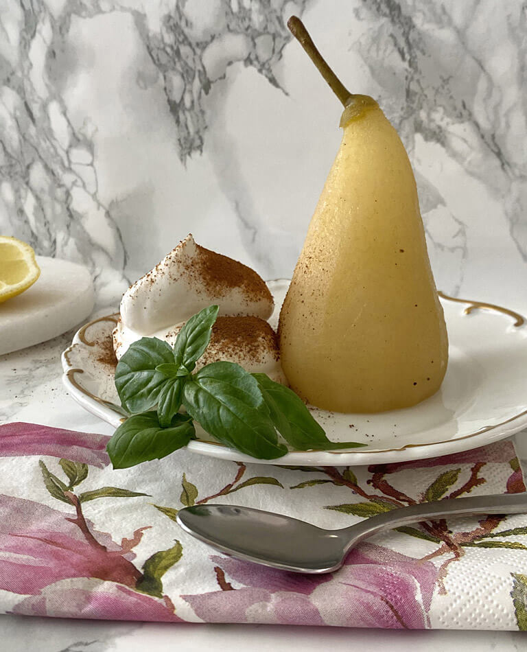 Inkokta päron med ingefära, grädde och kanel på ett fat med en sked. 