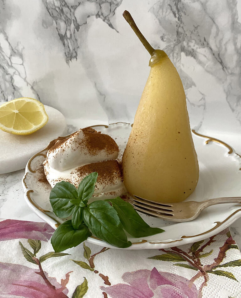 Inkokta päron med ingefära, grädde och kanel på ett fat med en gaffel. 